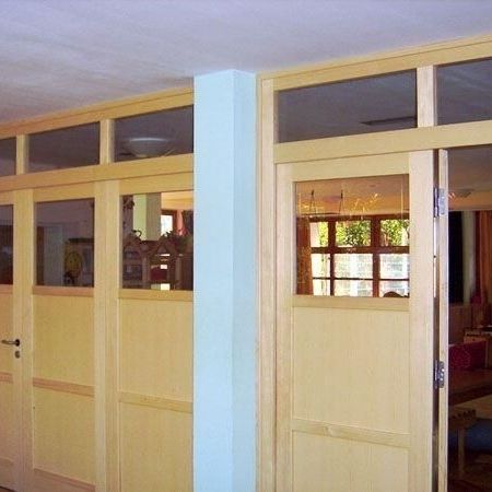 Ein Raum mit Holzfußboden und Holzfenstertüren, der eine warme und einladende Atmosphäre ausstrahlt