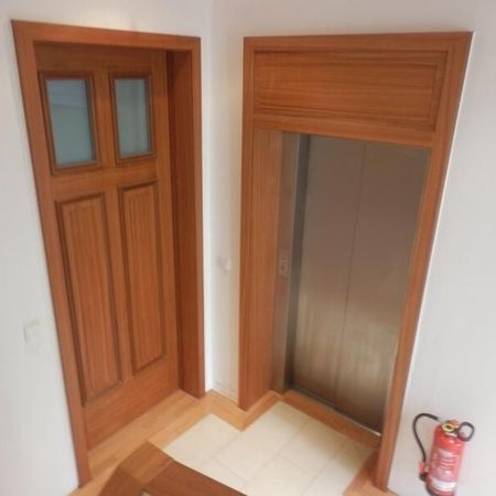 Eine Holztür mit Glaselementen neben einem Aufzug