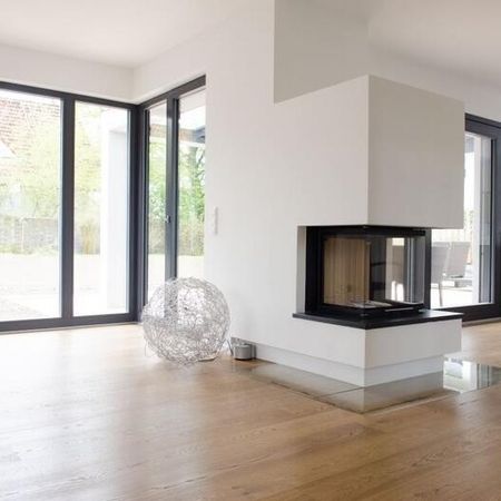 Modernes Wohnzimmer mit einem Kamin und großen Fenstern, die viel Tageslicht hereinlassen